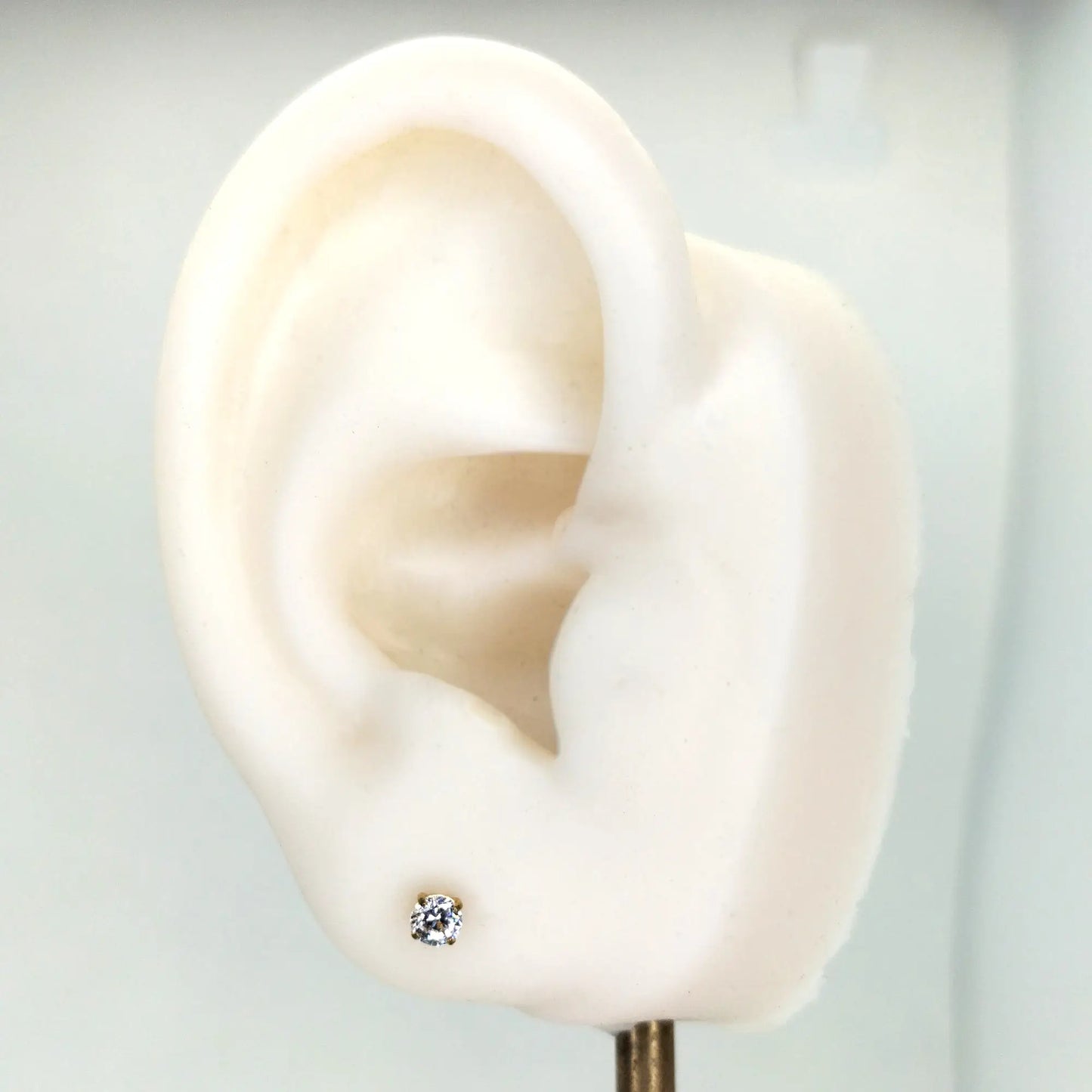 Piercing labret en titane ASTM F-136 finition PVD Or, présenté sur le lobe d'une oreille artificielle