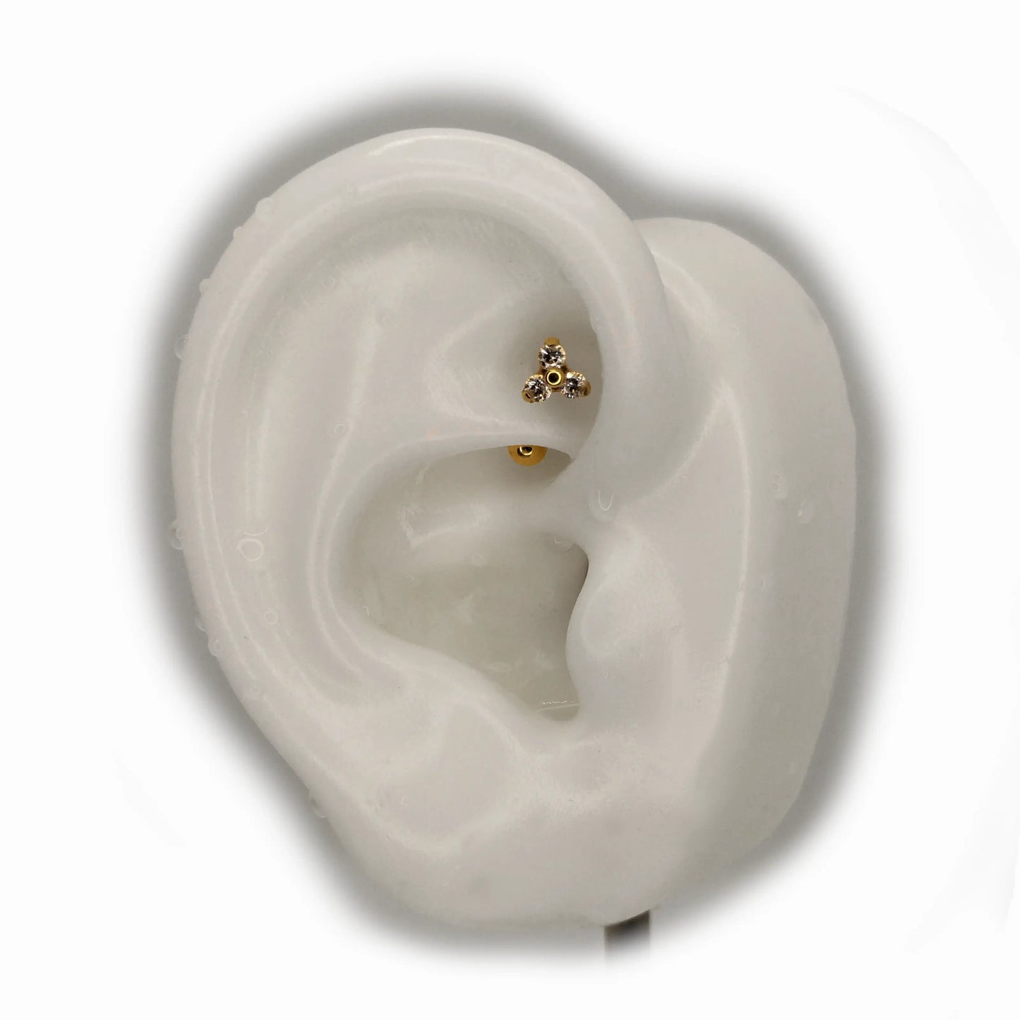 Piercing rook en titane avec design Trinity en zirconium, finition PVD or porté sur un rook en silicone