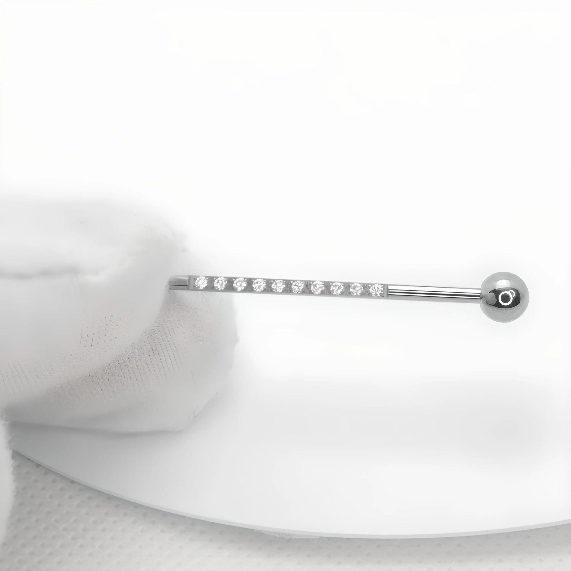Présentation d'une barre de piercing industriel d'une longueur de 38 mm, tenue dans un gant de coton