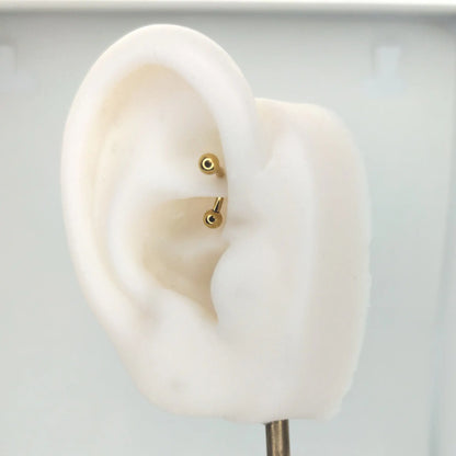 Piercing de type banane en titane avec finition PVD or, présenté sur le rook d'une oreille artificielle