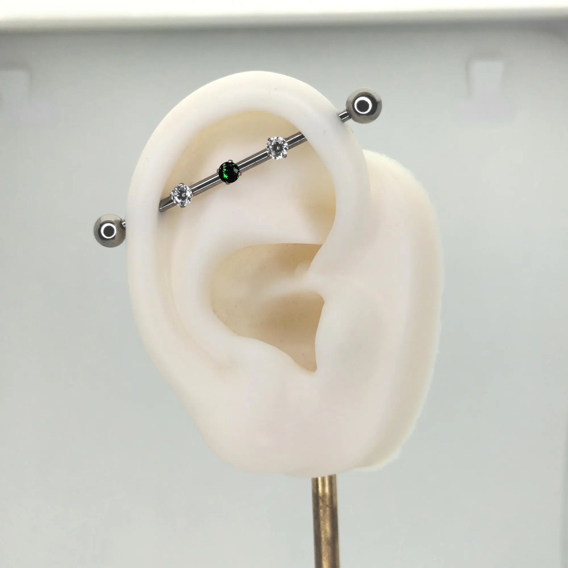 Barre de piercing industriel en titane ASTM F-136 présentée sur une oreille artificielle